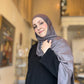 Woman wearing a gray hijab and black outfit indoors