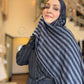Woman wearing a blue and gray striped hijab in an indoor setting