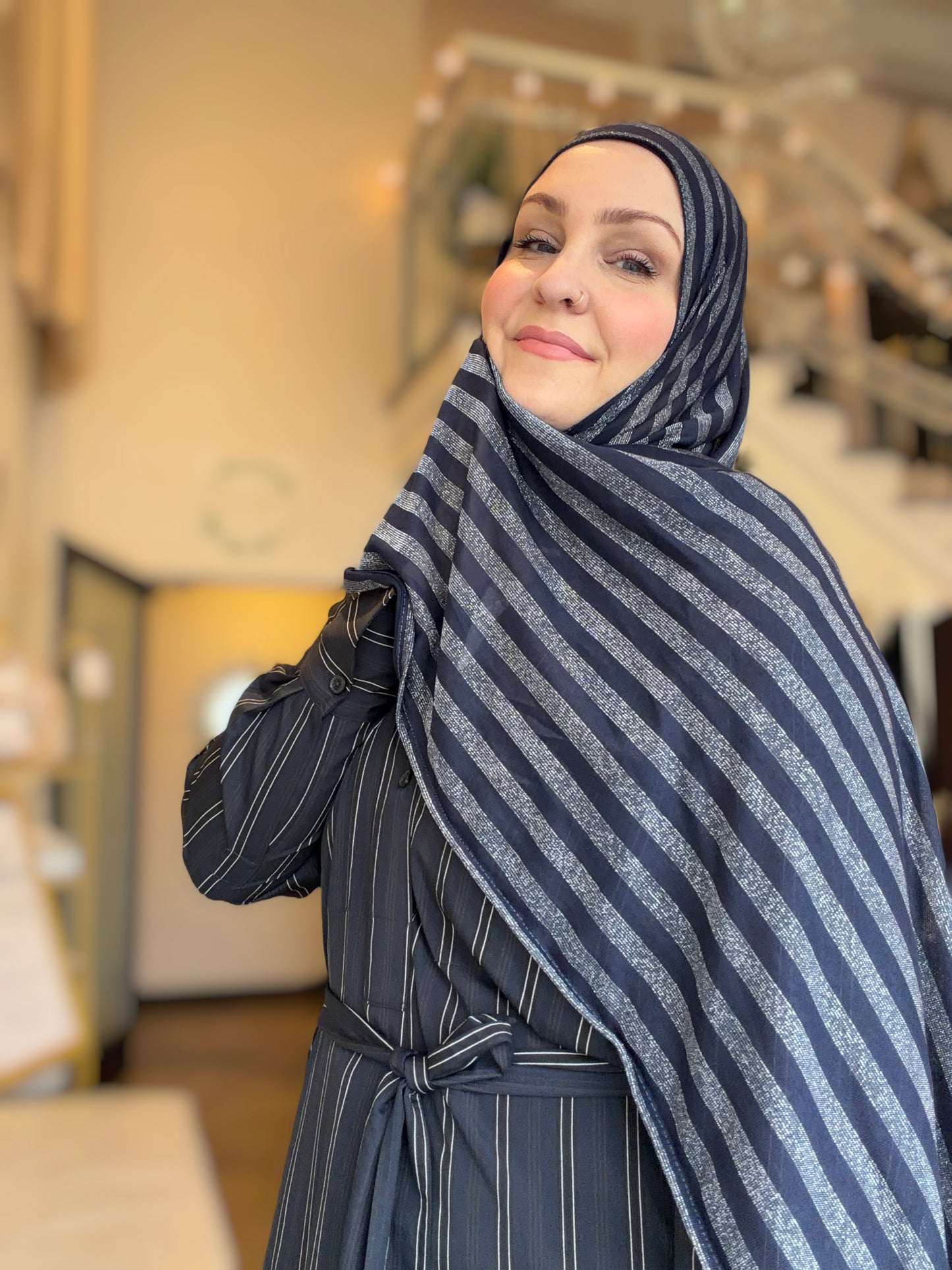 Woman wearing a blue and gray striped hijab in an indoor setting