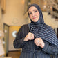 Woman wearing a dark blue hijab and matching outfit indoors