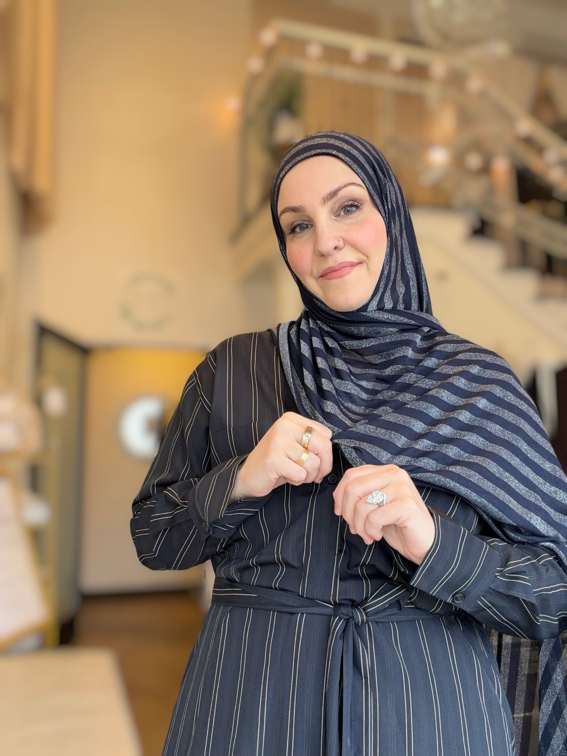 Woman wearing a dark blue hijab and matching outfit indoors