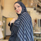 Woman wearing a striped headscarf and coat in an indoor setting