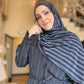 Woman wearing a blue striped hijab and matching outfit indoors