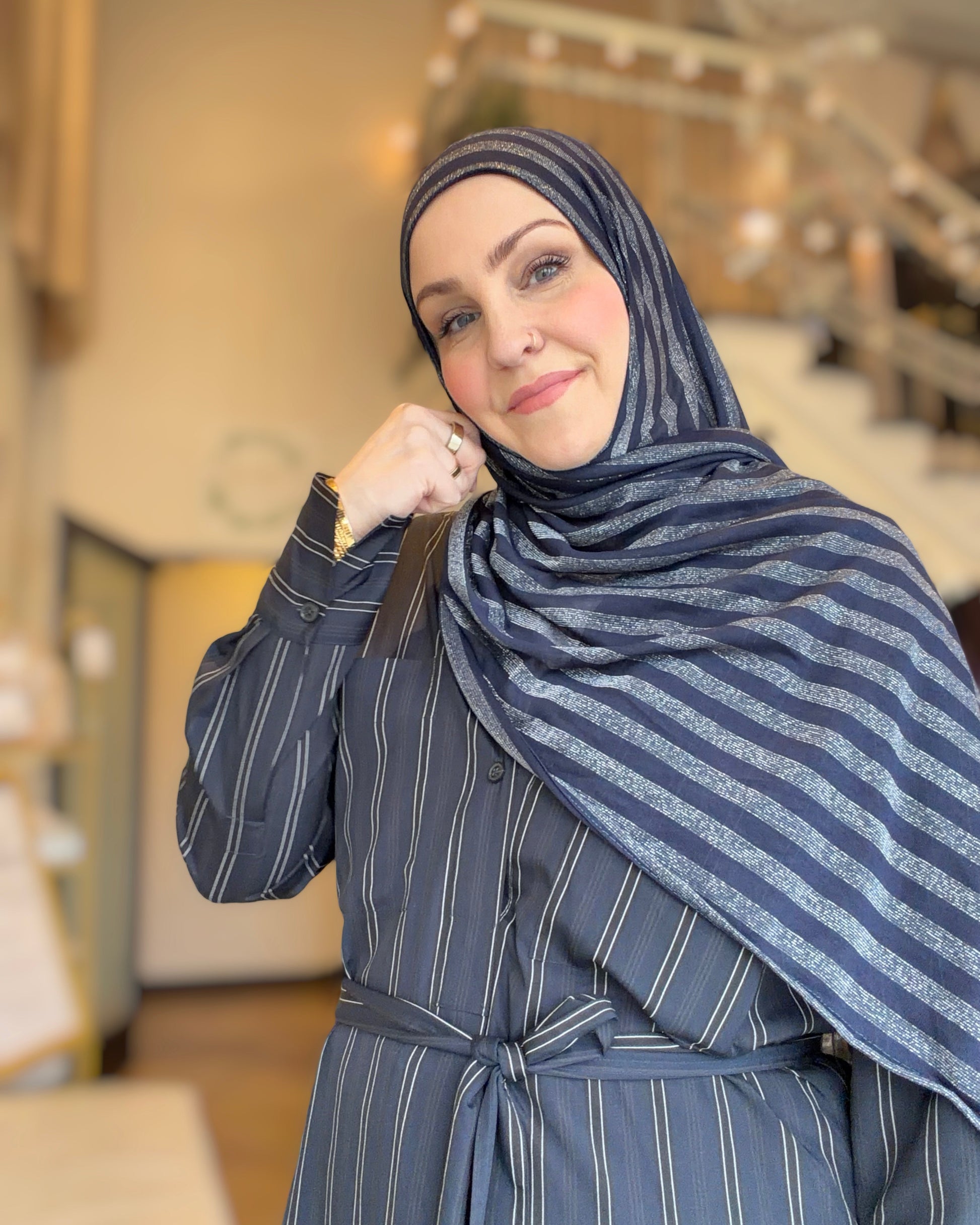 Woman wearing a blue striped hijab and matching outfit indoors