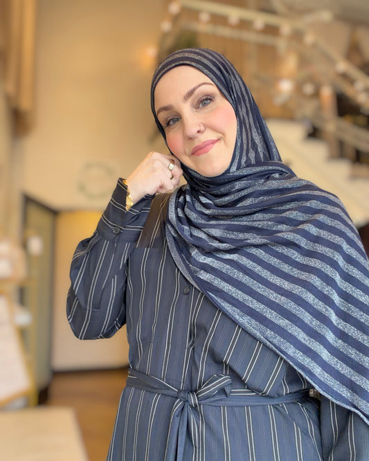 Woman wearing a blue striped hijab and matching outfit indoors